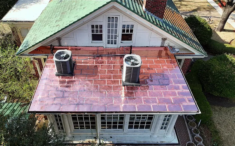 Low-slope porch roof newly covered in flat-seam copper panels, seen from above with two air-conditioning units on it