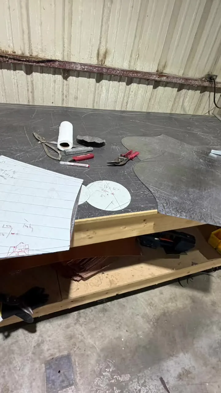 Shop bench with a paper template, a tape measure and snips laid on copper sheet