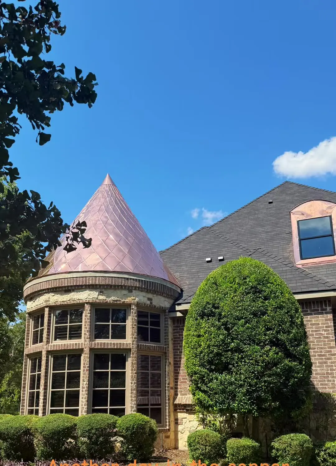 Conical turret roof in new copper on a brick house with a curved bay window below, under a blue sky