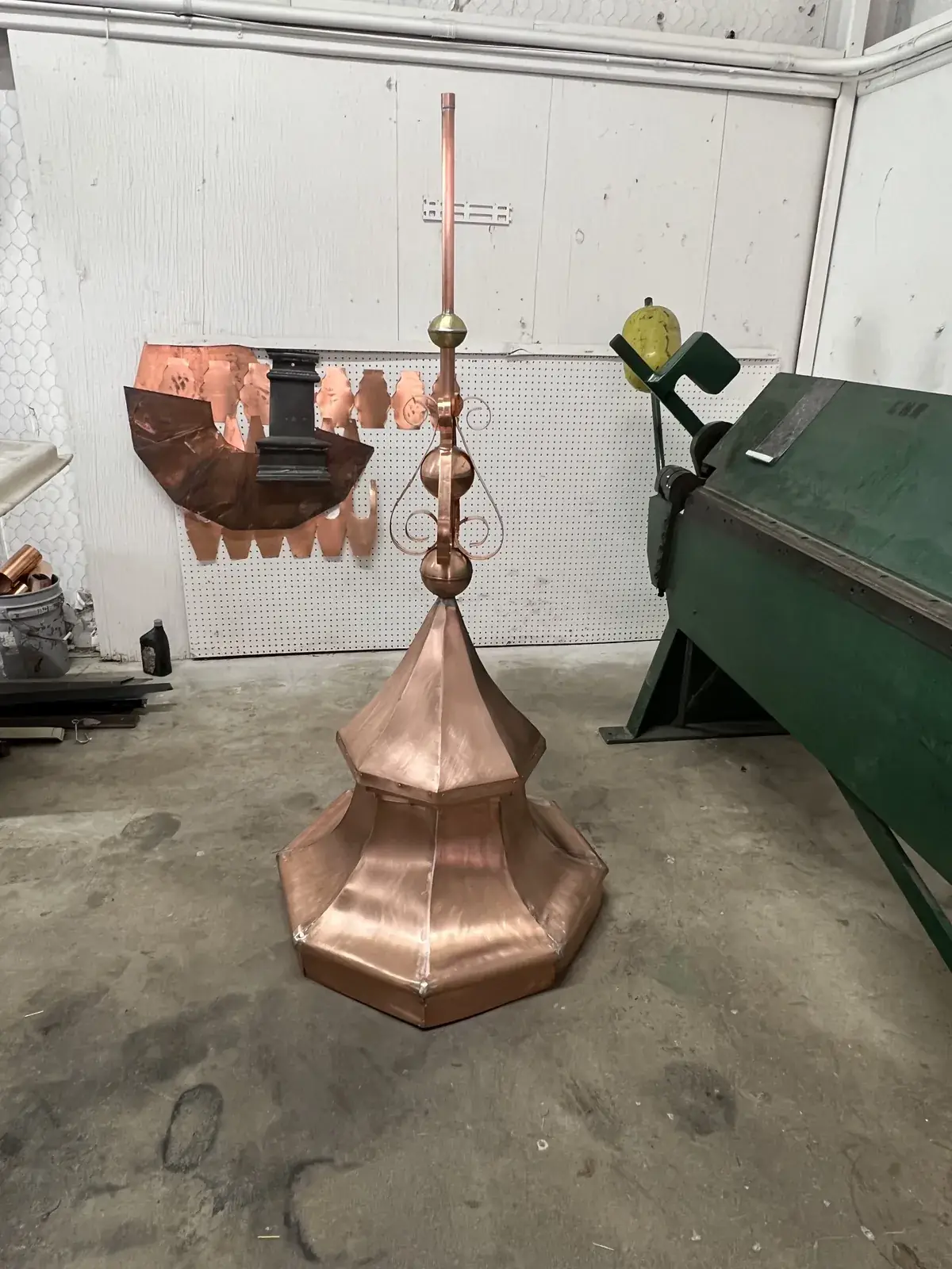 Ornamental copper finial with scrollwork, stacked balls and a spire over an octagonal bell base, in the shop
