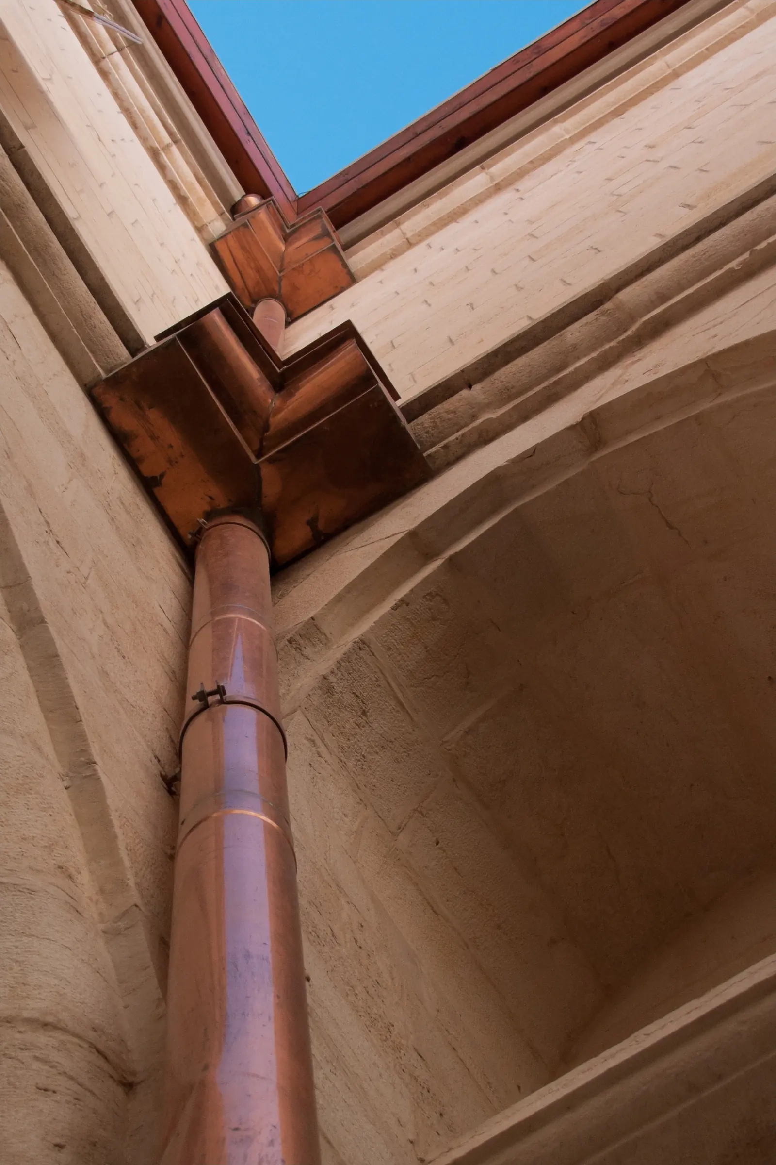 Copper gutter corner and outlet feeding a copper downspout, seen from below